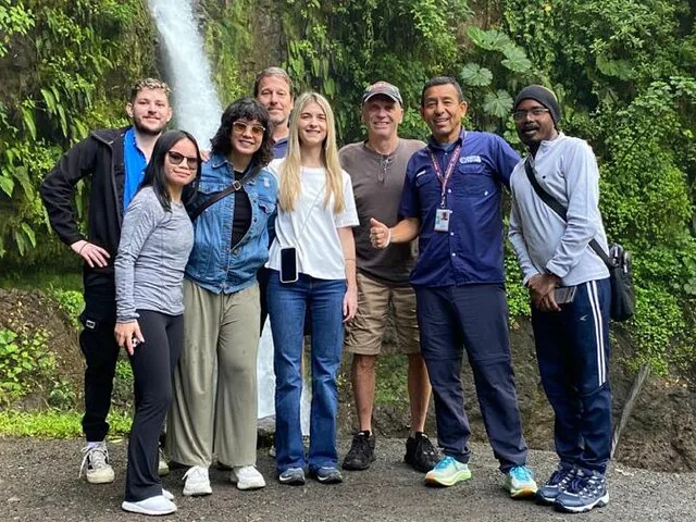 Touristengruppe posiert gemeinsam an einem wunderschönen Wasserfall im Dschungel