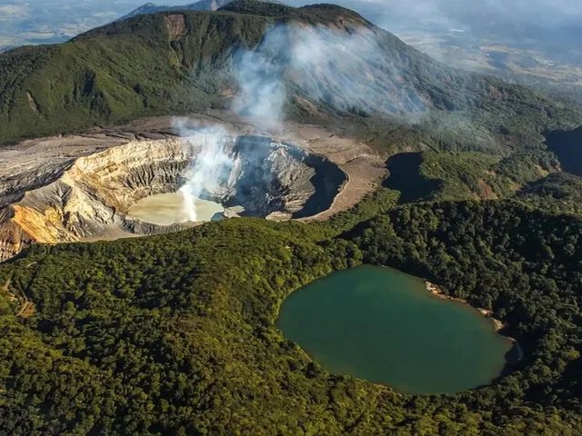 Aerial view of Poas Volcano crater with steaming vent and green lagoon